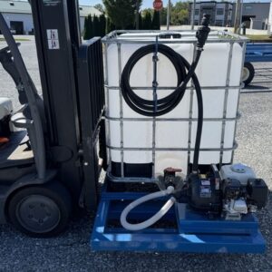 A forklift moves a 275 Gallon Tote Pallet Tanker with a metal frame, hoses, and pump attached on a blue metal pallet outdoors.